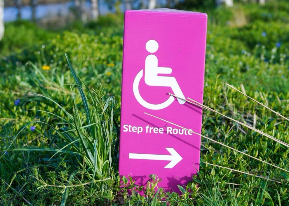 Pinkfarbenes Hinweisschild mit Rollstuhlfahrer-Symbol