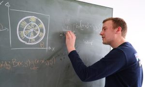 Physiker schreibt mathematische Formeln an eine Tafel