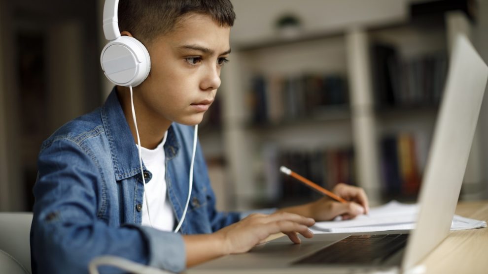 Junge mit Kopfhörer beim Arbeiten an einem Laptop