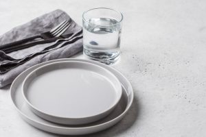 Symbolbild für Fasten: leere Teller und ein Wasserglas