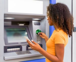 Frau mit Bankkarte an einem Geldautomaten