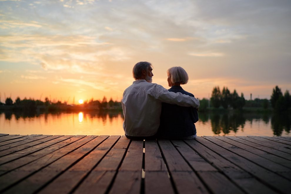 Älteres Paar an Seeufer bei Sonnenuntergang