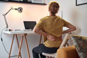 Frau mit Rückenschmerzen an einem Schreibtisch