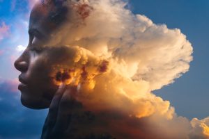 Symbolbild Träumen: Kopf einer Frau, der zur Hälfte von Wolken vernebelt ist