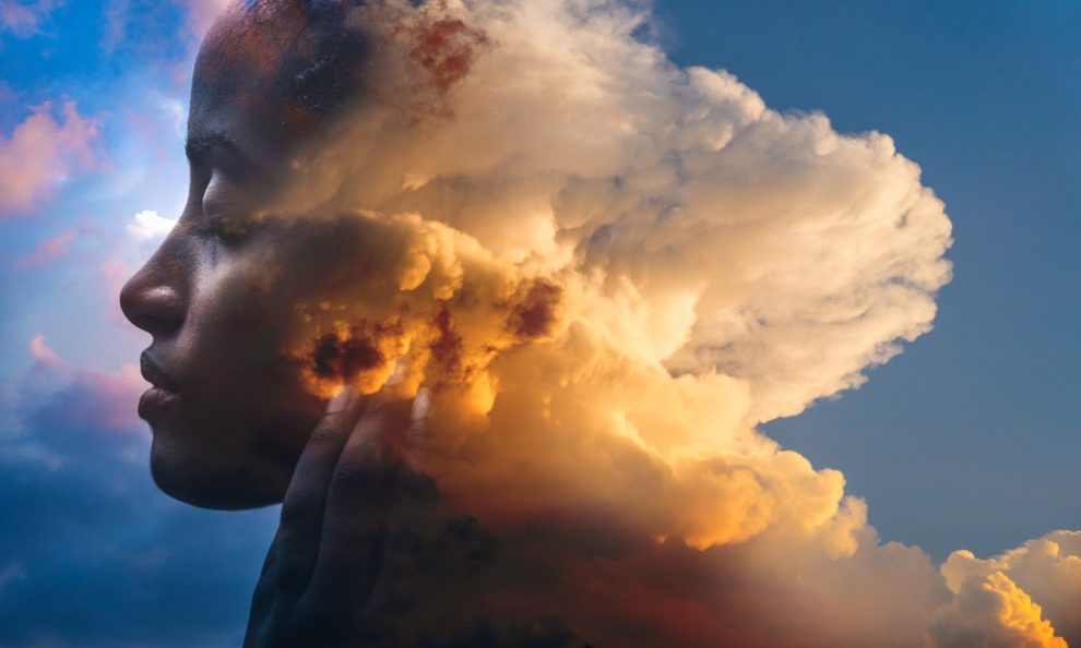 Symbolbild Träumen: Kopf einer Frau, der zur Hälfte von Wolken vernebelt ist